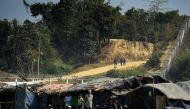 A Myanmar security personnel keeps watch along the Myanmar-Bangladesh border as Rohingya refugee sit outside their makeshifts shelters near Tombru, in the Bangladeshi district of Bandarban on March 1, 2018. AFP / MUNIR UZ ZAMAN