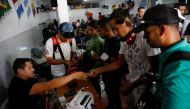 Federico Urquiola (2nd R), 27, a worker in a construction business who is traveling by bus from Caracas to Peru, exchanges money in Cucuta, Colombia, November 8, 2017. Federico said he struggled to get contracts for his construction business and was often