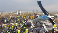 Nepali rescue workers gather around the debris of an airplane that crashed near the international airport in Kathmandu on March 12, 2018. AFP / Prakash Mathema 