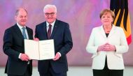 German President Frank-Walter Steinmeier (C) hands over the certificate of appointment to the new German Finance Minister and Vice-Chancellor Olaf Scholz as German Chancellor Angela Merkel looks on on March 14, 2018 at Bellevue Palace in Berlin. AFP / Ste