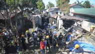Rescuers and investigators stand at the site where a twin-engine plane crashed into a house just after taking off in Plaridel town, Bulacan province, north of Manila on March 17, 2018.  AFP / STR
