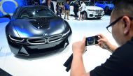 A man takes a photo of a BMW i8 hybrid sports car during the annual Bangkok International Motorshow in Bangkok on April 2, 2018. AFP / Lillian Suwanrumpha


