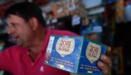 A newsstand vendor shows a box of collectible trading cards of the album Russia 2018 in Caracas on April 2, 2018. Due to the economic crisis in Venezuela, fans are not able to collect the FIFA World Cup Russia 2018 picture cards. AFP / Federico Parra 