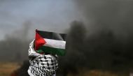 A demonstrator with a Palestinian flag looks on during clashes with Israeli troops at the Israel-Gaza border at a protest demanding the right to return to their homeland, in the southern Gaza Strip April 6, 2018. Reuters/Ibraheem Abu Mustafa 