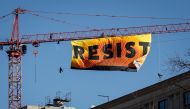 Protesters unfurl a banner atop a crane at the construction site of the former Washington Post office building, January 25, 2017. (Drew Angerer / Getty Images / AFP) 
