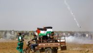 Palestinians run for cover from tears gas fired by Israeli security forces during clashes following a protest on the Israel-Gaza border east of the Jabalia refugee camp in the northern Gaza Strip on April 6, 2018.  AFP / Mohammed Abed