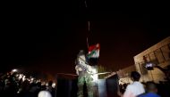 A member of forces of President Bashar al Assad holds a Syrian flag as buses carrying freed hostages and rebels who were evacuated from the rebel-held city of Douma drive at Wafideen camp in Damascus, Syria April 8, 2018. Picture taken April 8, 2018. REUT