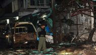 A member of a Thai police bomb squad inspects the site of a bomb blast in Sungai Kolok, Narathiwat province, on April 9, 2018.  / AFP / Madaree TOHLALA 
