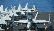 Sailors preapre FA-18 Hornet fighter jets for take off during a routine training aboard the US aircraft carrier Theodore Roosevelt in the South China Sea on April 10, 2018.  AFP / Ted Aljibe
