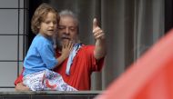 Luiz Inacio Lula da Silva holds his grandson Pedro while waves supporters from the balcony of his apartment in Sao Bernardo do Campo, some 25 km from Sao Paulo,  Brazil, on March 13, 2016. AFP / Nelson Almeida