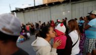 A member of a migrant caravan from Central America kisses a baby as they pray in preparation for an asylum request in the U.S., in Tijuana, Baja California state, Mexico April 28, 2018. REUTERS/Edgard Garrido