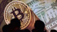 An image of Bitcoin and US currencies displayed on a screen as delegates listen to a panel of speakers during the Interpol World Congress in Singapore on July 04, 2017. (AFP / Roslan Rahma) 
