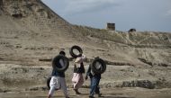 Afghan men carry tires as they walk near the old fortress of Bala Hissar in Kabul on May 6, 2018. / AFP / WAKIL KOHSAR
