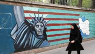 An Iranian woman walks past a mural on the wall of the former US embassy in the Iranian capital Tehran on May 8, 2018.  AFP / Atta Kenare