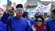 File photo of Malaysia's then-Prime Minister Najib Razak (L) and his wife Rosmah Mansor (R) wave as they arrive at the nomination centre to hand over election documents in Pekan, April 28, 2018. / AFP / Mohd RASFAN 