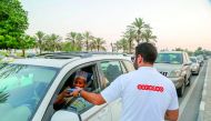 An Ooredoo volunteer distributing dates and water at Doha Corniche.