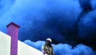 A firefighter works to douse the fire inside a warehouse caused by a truck in New Delhi on May 29, 2018.  AFP / Chandan Khanna