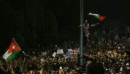 Protesters wave flags near Jordanian security forces during a demonstration outside the prime minister's office in the capital Amman late on June 3, 2018.  AFP / Khalil MAZRAAWI
