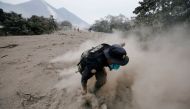 A police officer stumbles while running away after a the Fuego volcano spew new pyroclastic flow in the community of San Miguel Los Lotes in Escuintla, Guatemala, June 4, 2018. REUTERS/Luis Echeverria