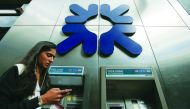 A woman looks at her smart phone as she passes cash machines (ATMs) outside a Royal Bank of Scotland (RBS) bank branch in central London In this file photo taken on August 04, 2017.  AFP / Daniel Leal-Olivas