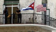 Two men stand on a balcony next to the Cuban and USA National Flags in Havana, Cuba, March  17,  2016. EPA / Ernesto Mastrascusa
