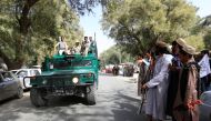 A Taliban (R) stands as Afghan security forces ride on an army vehicle during celebration ceasefire in Bati Kot district of Nangarhar province, Afghanistan June 16, 2018.REUTERS/Parwiz
