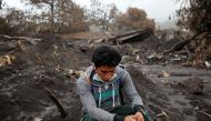A resident sits on the rubble as people continue to search for remains of victims after the eruption of the Fuego volcano at San Miguel Los Lotes in Escuintla, Guatemala, June 17, 2018. REUTERS/Luis Echeverria 