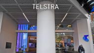 A man (R) sits by the entrance to a Telstra store on Melbourne's central business district on June 20, 2018.  / AFP / William WEST 