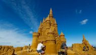 A sand carver works on a sculpture during the Sand Sculpture Festival 