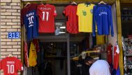 This photograph taken, shows a Kosovo Albanian pedestrian walking past a replica football jersey of Switzerland's midfielder Granit Xhaka outside a shop in the Kosovo capital Pristina. Football-fever among Kosovans for the World Cup has skyrocketed as thr