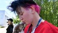 A volunteer of Clean Futures Fund (CFF) holds a stray puppy outside the improvised animals hospital just near the Chernobyl power plant on June 8, 2018. / AFP / Sergei SUPINSKY 