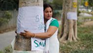 A woman hugs a tree during 