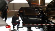 This picture taken on July 1, 2018 in Aulnay-sous-Bois, north of Paris shows a forensic police officer investigating a car abandoned by French armed robber Redoine Faid at O'Parinor shopping mall parking after his escape onboard a helicopter from a prison