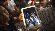 A family member shows a picture of four of the twelve missing boys near the Tham Luang cave at the Khun Nam Nang Non Forest Park in Mae Sai on July 2, 2018.  AFP / Lillian Suwanrumpha