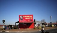 FILE PHOTO: A man pushes a wheelbarrow past a billboard of the Economic Freedom Fighters which is led by Julius Malema in Soweto,  South Africa,  August 5, 2016. Reuters/Siphiwe Sibeko