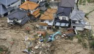 Rescue workers are seen next to houses damaged by a landslide following heavy rain in Hiroshima, western Japan, July 7, 2018. Kyodo/via REUTERS 