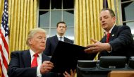 FILE PHOTO: US President Donald Trump hands Chief of Staff Reince Priebus (R) an executive order that directs agencies to ease the burden of Obamacare, after signing it in the Oval Office in Washington, DC, U.S. January 20, 2017. Also pictured is White Ho