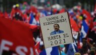 A supporter of embattled Nicaraguan President Daniel Ortega holds a placard reading 