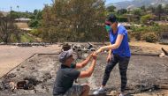 Ishu and Laura Rao, return to the rubble of their home which they lost in a wildfire, to retrieve their wedding ring, in Alameda, California, US, in this July 8, 2018 photo obtained from social media. Mike Eliason/Santa Barbara County Fire Department/via 