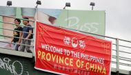 Residents walk past a banner reading 