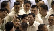 Philippine President Rodrigo Duterte poses for a selfie while surrounded by supporters and lawmakers after delivering his state of the nation address at Congress in Manila on July 23, 2018. (AFP / NOEL CELIS)