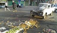 A handout picture released by the official Syrian Arab News Agency (SANA) on July 25, 2018 shows a member of the Syrian security forces walking past a truck damaged in a suicide attack in the southern city of Sweida. (AFP PHOTO / HO / SANA)