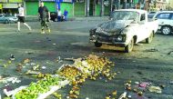 A handout picture released by the official Syrian Arab News Agency (SANA) on July 25, 2018 shows a member of the Syrian security forces walking past a truck damaged in a suicide attack in the southern city of Sweida. A string of suicide attacks in Syria b