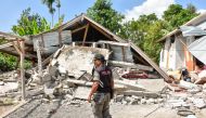 An Indonesian village security officer examines the remains of houses, after a 6.4 magnitude earthquake struck, in Lombok on July 29, 2018. (AFP / Aulia AHMAD)