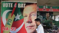 A man walks past a poster of Pakistan's cricketer-turned politician Imran Khan, and head of the Pakistan Tehreek-e-Insaf (Movement for Justice) party, at a market in Islamabad on July 27, 2018. (AFP / AAMIR QURESHI)