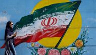 An Iranian woman walks past a mural of the Iranian flag in Tehran on October 14, 2017. (AFP) 