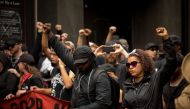 Members of ANTIFA get in formation after entering the security checkpoint required to enter the mall in downtown Charlottesville, Virginia, one-year after the violent white nationalist rally that left one person dead and dozens injured. / AFP / Logan Cyru