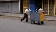 A man pushes a cart in front of closed stores at a commercial area in downtown Caracas, Venezuela August 21, 2018. REUTERS/Marco Bello