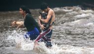Residents carry dogs through flood waters to dry land, after playing in the water briefly on the Big Island on August 23, 2018 in Hilo, Hawaii. Hurricane Lane has brought more than a foot of rainfall to some parts of the Big Island which is under a flash 