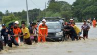 Residents negotiate a flooded road after rampaging waters from a dam spillway submerged villages in Bago region, central Myanmar on August 29, 2018. AFP / Thet AUNG